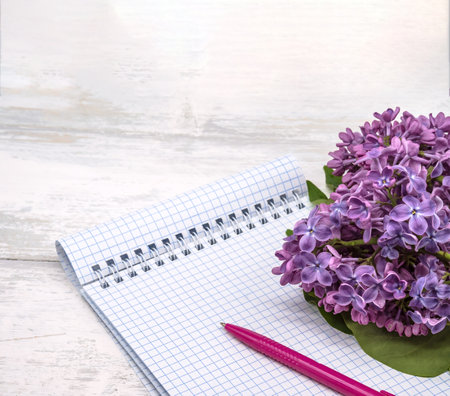 A notebook and a flower. A notebook with a pen and flowers. Spiral notebook and pen. Copybook on a wooden background.の写真素材