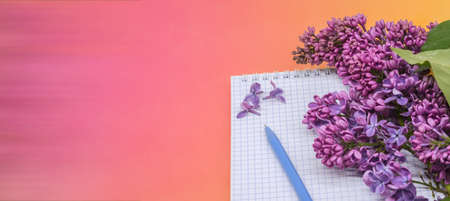 Spiral notebook and pen. Notepad with pen and flowers. Notebook lilacs on red background.の写真素材