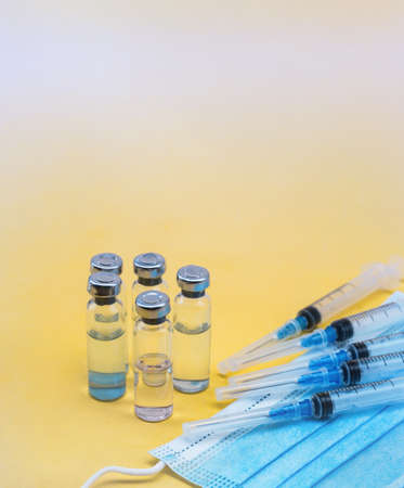 Injections and medications. Medical ampoules and mask. Syringes and ampoules. Yellow background.の写真素材