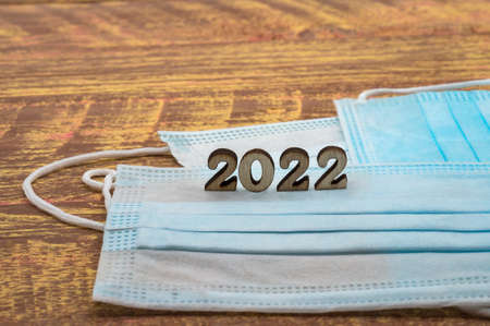 Canceled mask mode. Used face mask. A wrinkled medical mask. 2022 numbers on wooden background.