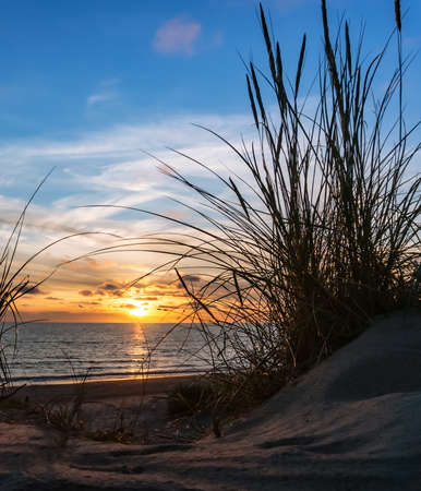 Reflection of sunlight in the sea waves. Red and yellow sky in the rays of the sunset. Sunset over the sea. Vertically.の写真素材