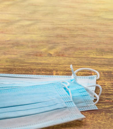 Disposable surgical mask. Stack of surgical masks on wooden table. Blue medical mask. Medical protective masks on wooden background. Vertically.の写真素材