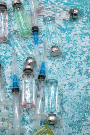Medical syringe vials on a green background. Vaccination against covid-19. Prevention of seasonal diseases. Vertically.の写真素材