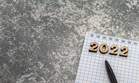 Notebook and pen on the grey. Wooden numbers date 2022. A blank sheet of paper and a black pen.の写真素材