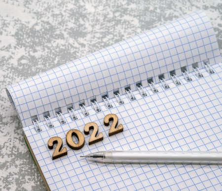 Notebook and pen on the grey. Wooden numbers date 2022. A blank sheet of paper and a white pen.の写真素材