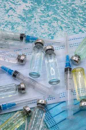 Medical vials, syringes and mask on a green background. Prevention of seasonal diseases. Vaccination against . Vertically.の写真素材