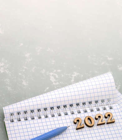 Notebook and pen on the gray. Wooden numbers date 2022. A blank sheet of paper and a blue pen.の写真素材
