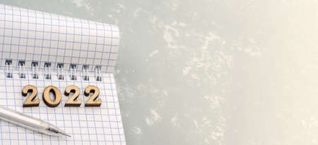 Notebook and pen on the gray. Wooden numbers date 2022. A blank sheet of paper and a white pen.の写真素材