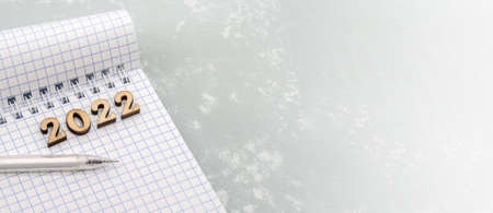 Notebook and pen on the gray. Wooden numbers date 2022. A blank sheet of paper and a white pen.の写真素材