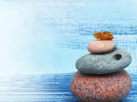 A pyramid of sea stones on a blue background. The sea stones are stacked in a column.の写真素材