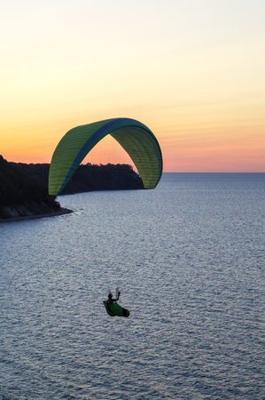 A paraglider at sunset. Paraglider on the seashore. Paraglider in the sky over the sea.のeditorial素材