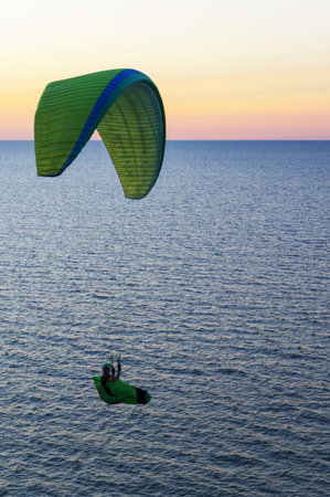 Baltic Sea, Kaliningrad region, Russia, 22 August 2022. A paraglider at sunset. Paraglider on the seashore. Paraglider in the sky over the sea.のeditorial素材