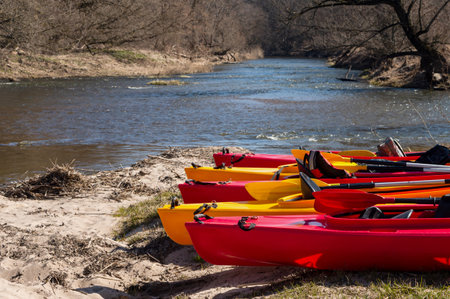Active pastime of the weekend. Sports tourism. Kayak on the river bank. Kayak rafting in the spring. Kayaks made of yellow and red plastic.の写真素材