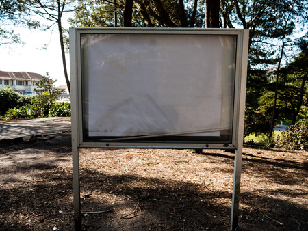 A plain signpost situated in a rural area surrounded by trees.