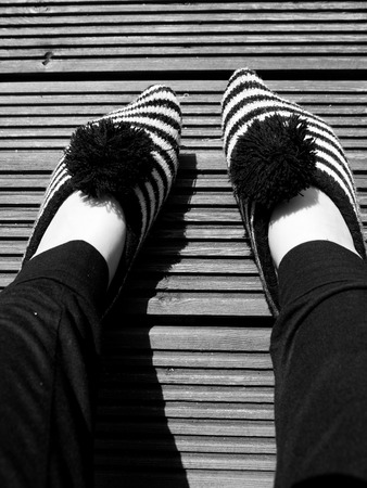 Black and white image of feet with striped sock on top of a striped wood texture.の写真素材