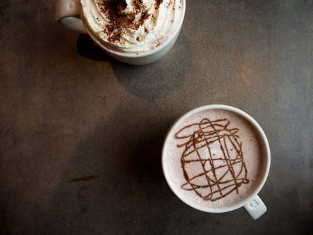 Two mugs of coffee and hot chocolate from a tabletop perspective on a granite surface.の写真素材