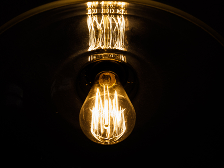 An old fashioned lightbulb illuminates in the darkness