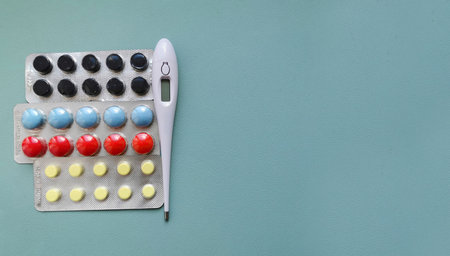 Pills and thermometer on blue background. Top view with copy spaceの写真素材