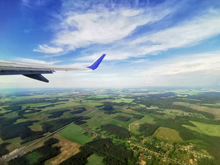 Aerial view of airplane wing on blue sky and green field.の写真素材