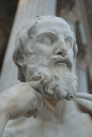 a sculpture of a thinking philosopher with a pencil in his hand
