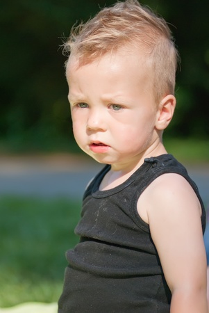 a worried looking caucasian boy sitting outsideの写真素材
