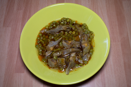 Plate with artichokes and peas on a wooden table seen close upの写真素材
