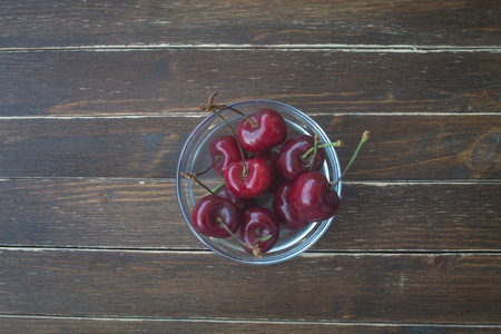 cherries inside transparent bowl on a wooden table top viewの写真素材