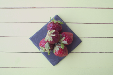 strawberries on slate on a green wooden table viewed from aboveの写真素材