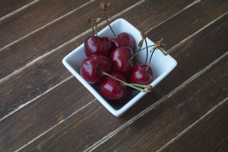 Cherries inside bowl on a wooden tableの写真素材