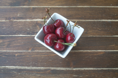 cherries inside bowl on a wooden table seen from aboveの写真素材