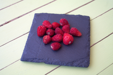 strawberries on slate on a green wooden table viewed from close upの写真素材