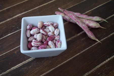 Beans in white bowl on a wooden table seen close upの写真素材