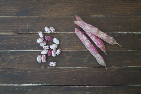 Beans with pods on a wooden table viewed from above