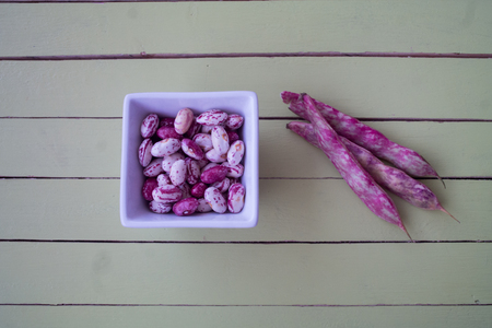 Beans in white bowl on a green wooden table seen from aboveの写真素材
