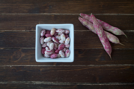 Beans in white bowl on a wooden table seen from aboveの写真素材