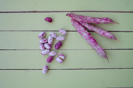 Beans with pods on a green wooden table seen from aboveの写真素材