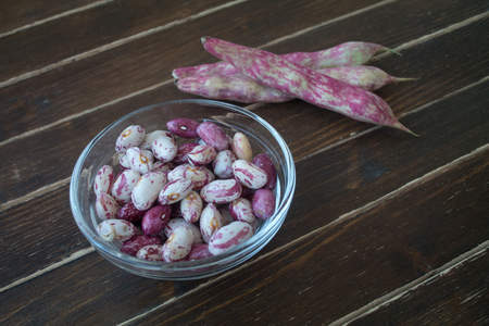 Beans in transparent bowl on a wooden table seen close upの写真素材