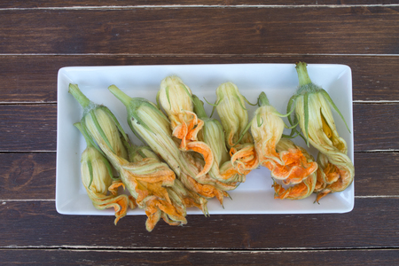 pumpkin flowers on white tray on a wooden table seen from aboveの写真素材