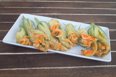 pumpkin flowers on white tray on a wooden table seen close upの写真素材