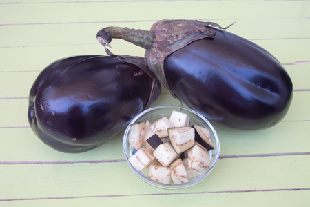 eggplants in cubes on a green wooden table viewed from close upの写真素材