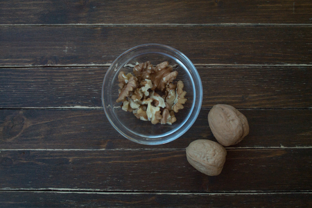 walnuts in a transparent bowl on a wooden table seen from aboveの写真素材