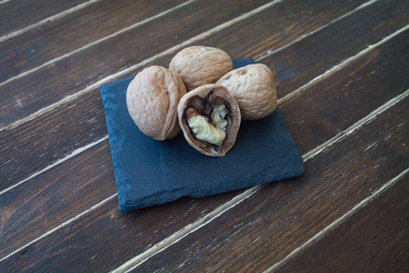 walnuts on a slate plate on a wooden table seen close upの写真素材