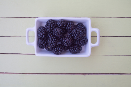blackberries on white tray on a green wooden table seen from aboveの写真素材