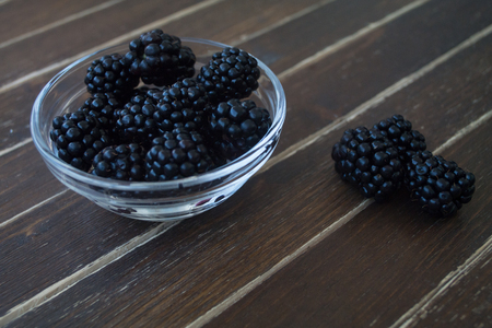 blackberries on transparent bowl on a wooden table seen close upの写真素材