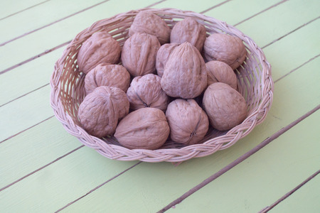 walnuts inside a wicker basket on a green wooden table seen close upの写真素材