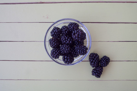blackberries on transparent bowl on a green wooden table seen from aboveの写真素材