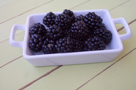 blackberries on white tray on a green wooden table seen close upの写真素材