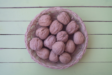walnuts inside a wicker basket on a green wooden table seen from aboveの写真素材