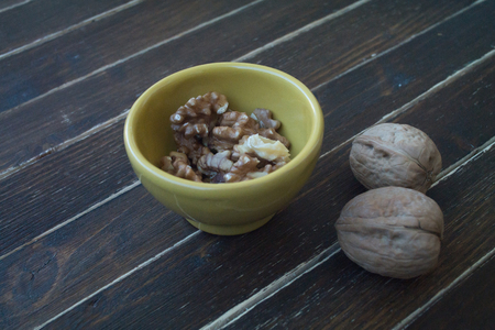 walnuts in a yellow bowl on a wooden table seen closelyの写真素材