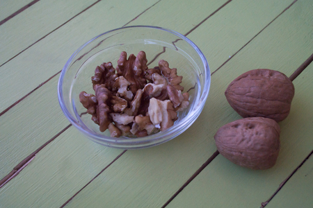 walnuts in a transparent bowl on a green wooden table seen close upの写真素材
